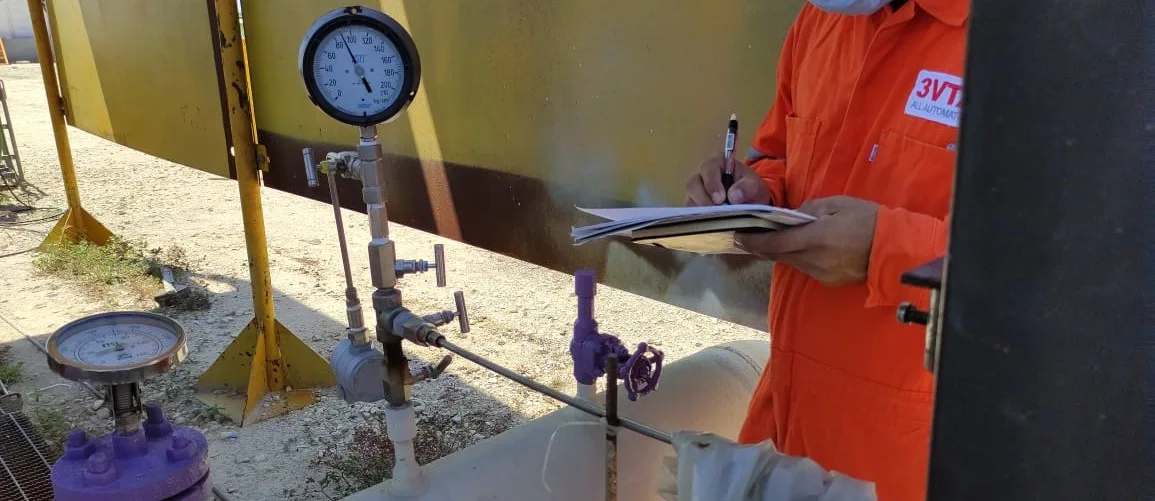 Operador industrial midiendo presión y realizando inspección de válvulas en planta de procesos, monitoreo y mantenimiento técnico